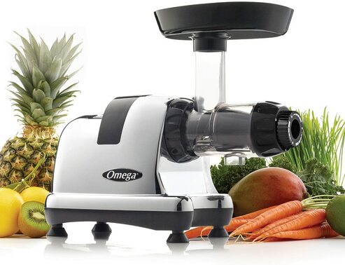 Juicer next to fresh fruits and vegetables