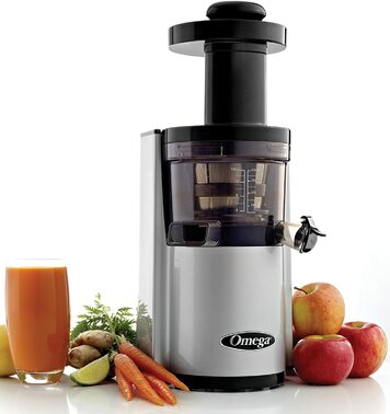 Upright juicer next to a glass of carrot juice